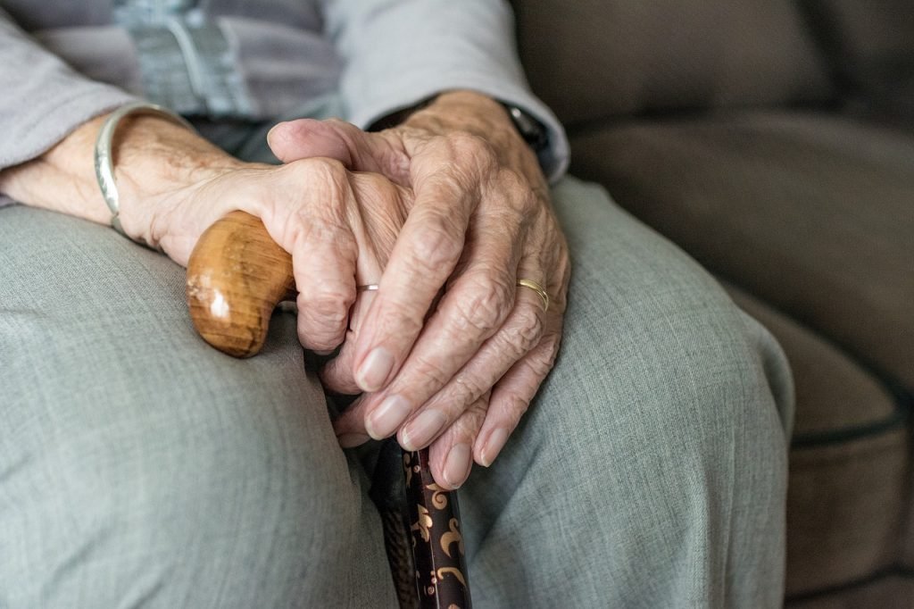 An elderly person holding their cane.