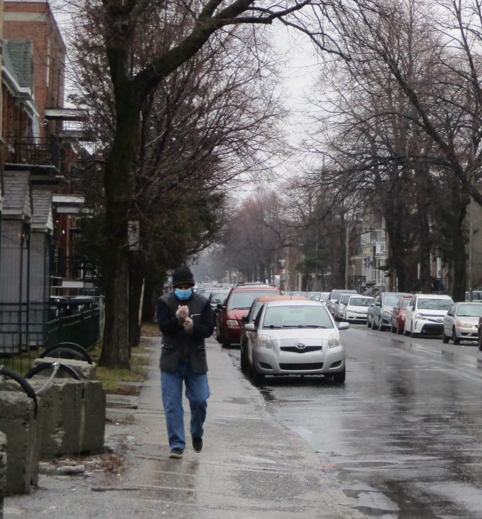 A man adjusting his gloves and mask on an empty street in Parc Extension. Photo: Avleen K Mokha