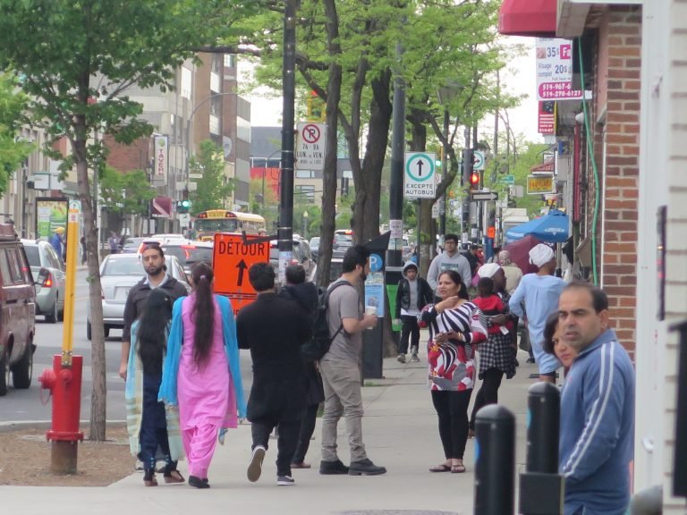 Residents walk down a busy street in Park Extension.